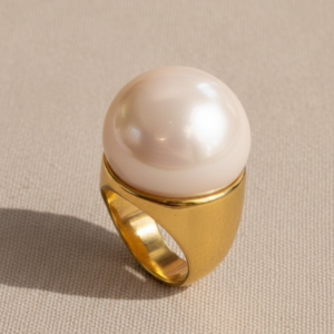 Anillo de acero dorado bold con gema esférica nacarada de gran formato estilo editorial marca Cianna