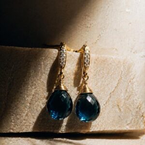 Aretes colgantes con piedra natural London Blue facetada y detalle de microzirconias en chapa de oro 22k marca Cianna