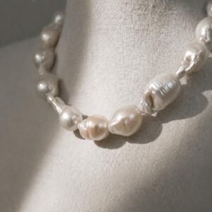 Modelo luciendo collar de perlas barrocas naturales gigantes con matices tornasol marca Cianna