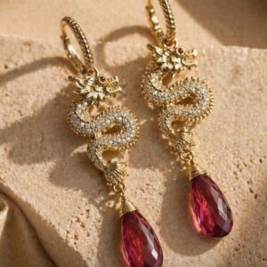 Aretes de dragon con micro zirconias incrustadas y gotas colgantes de rubí natural facetado en baño de oro.
