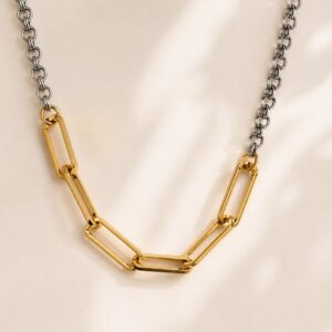 Collar de eslabones bicolor con cadena de rodio y eslabones frontales en chapa de oro de 22k sobre fondo de satín.