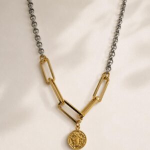 Collar bimetálico de eslabones en rodio y chapa de oro de 22k con dije de medalla de San Benito sobre fondo de satín.